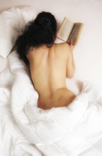 Naakte vrouw leest sexverhaal in bed
